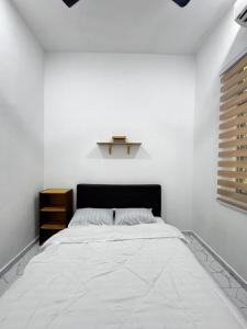 a white bedroom with a bed with a black headboard at NY VILLA Homestay in Kota Bharu