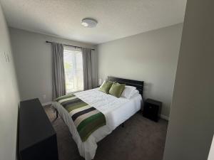 a bedroom with a bed with green pillows and a window at Home Away from Home in Brandon
