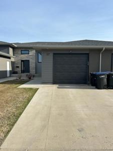 a house with a garage door and two trash cans at Home Away from Home in Brandon