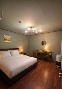 a bedroom with a large bed and a table at Gangneung Wheel Hotel in Gangneung