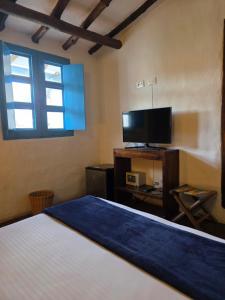 a bedroom with a bed and a flat screen tv at Casa Raisol Barichara in Barichara