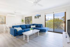 a living room with a blue couch and a table at Callala On King - Pet Friendly - Swimming Pool in Callala Beach