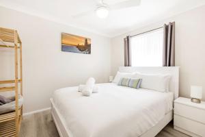 a bedroom with a white bed and a window at Callala On King - Pet Friendly - Swimming Pool in Callala Beach +19 photos