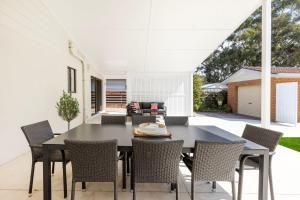 an outdoor dining room with a black table and chairs at Callala On King - Pet Friendly - Swimming Pool in Callala Beach