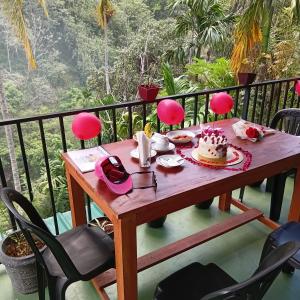 a table with a cake on top of a balcony at Rawana River Edge in Ella