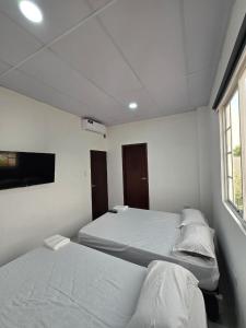 a bedroom with two beds and a tv on the wall at Hammerhead Shark Apartment in Puerto Baquerizo Moreno
