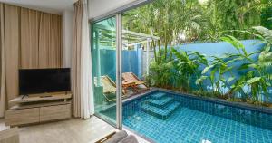a room with a swimming pool and a balcony with a television at Villa Sonata Phuket in Chalong