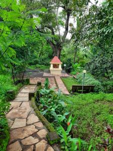 a garden with a stone walkway with a small building at Alhaad valley views in Mulshi