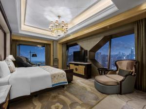 a bedroom with a large bed and a chandelier at Wanda Reign Wuhan in Wuhan