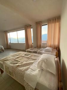 two beds in a bedroom with two windows at Casa Artesana Maras URU CUZ PE in Maras