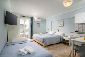 a room with two beds and a kitchen with a tv at Aris Studios in Hersonissos +80 photos