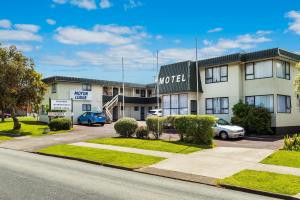 a hotel with cars parked in a parking lot at Takapuna International Motor Lodge in Auckland