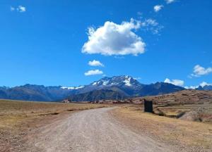 a dirt road in the middle of a field with mountains at Casa Artesana Maras URU CUZ PE in Maras +13 photos