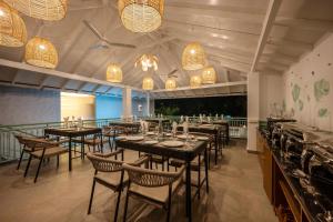 a dining room with tables and chairs and chandeliers at Yellowstone Resort Arambol in Arambol