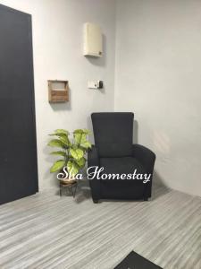a black chair in a room with a plant at SHA HOMESTAY Budget in Tampin