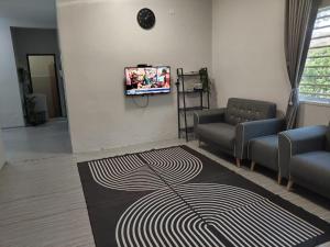 a living room with a couch and a tv on a wall at SHA HOMESTAY Budget in Tampin