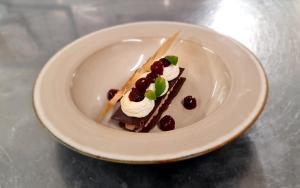 a piece of cake with whipped cream and berries on a plate at Hotel des Postes in Houffalize