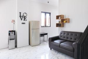 a living room with a couch and a refrigerator at Aurora House Surabaya in Wijung