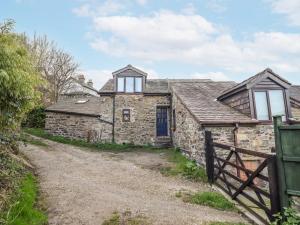 an old stone cottage with a blue door on a dirt road at Dovetail Cottage in Llangollen