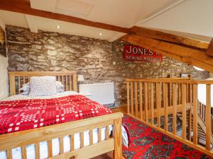 a bedroom with a red bed and a stone wall at Dovetail Cottage in Llangollen