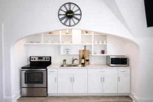 a kitchen with white cabinets and a clock above the sink at Game Room Fun Extended Stay Friendly in Danielson