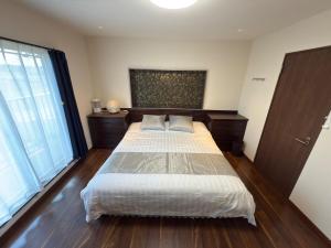 a bedroom with a large bed with wooden floors at House KIMIJIMA in Yachimata