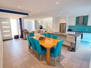 a kitchen and dining room with a wooden table and blue chairs at Waves at Jurien, Villa 9-23 Dalton Street in Jurien Bay
