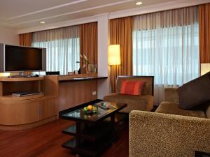 a living room with a television and a couch and a table at Impiana KLCC Hotel in Kuala Lumpur