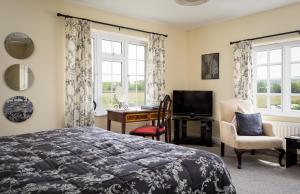 a bedroom with a bed and a desk and a television at Lowerfield Farm in Broadway