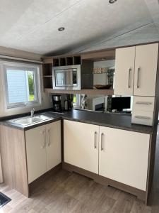 a kitchen with white cabinets and a sink at Chalet Vida in Petten