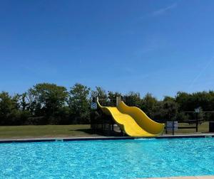 a playground with a yellow slide in a swimming pool at Chalet Vida in Petten
