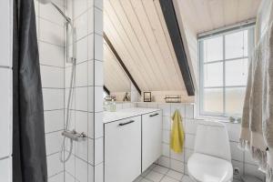 a white bathroom with a shower and a toilet at 274-Ringkobing-Nordso-Ferievej-86 in Nørre Lyngvig +25 photos