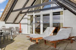 a patio with two chairs and a table and windows at 274-Ringkobing-Nordso-Ferievej-86 in Nørre Lyngvig