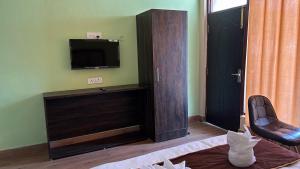 a living room with a television and a chair at Hotel Grand Shiva in Gupta Kāshi