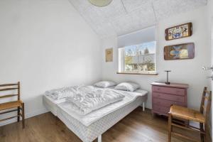 a bedroom with a bed and a window and a chair at 1616-Frederiksvaerk-Skovbrynet-7 in Frederiksværk