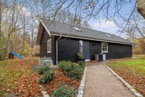 a small black house with a pathway in front of it at 1616-Frederiksvaerk-Skovbrynet-7 in Frederiksværk