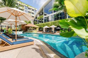 a swimming pool with lounge chairs and umbrellas next to a building at GreenLa by Villacarte in Layan Beach