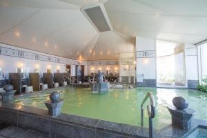 a swimming pool with a fountain in the middle of a building at Hotel Monterey Edelhof Sapporo in Sapporo