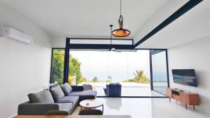 a living room with a couch and a large window at Villa Lumina, Koh Samui in Chaweng Noi Beach