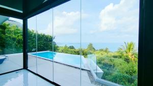 a glass house with a swimming pool and a view at Villa Lumina, Koh Samui in Chaweng Noi Beach