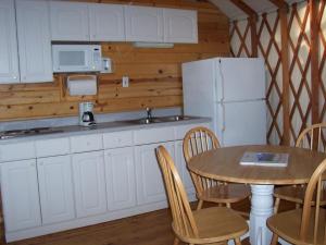 a kitchen with a table and a white refrigerator at Lake of the Springs Camping Resort Yurt 6 in Oregon House