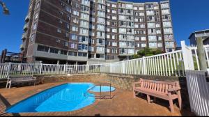 a swimming pool with a bench and a building at Ocean Whisper 405 in Scottburgh