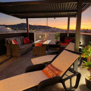 a patio with chairs and a couch on a roof at Moonlit Terrace Escape in St. Paul's Bay