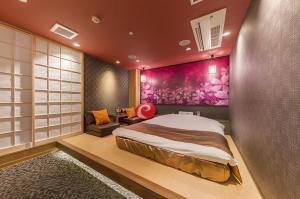a bedroom with a large bed and a purple wall at ホテル彩柏市若柴店 in Kashiwa