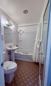 a bathroom with a toilet and a sink and a tub at John Day Motel in John Day