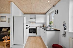 a kitchen with white cabinets and a wooden ceiling at LF10243-Thyholm-Krumborgvej-3 in Hvidbjerg