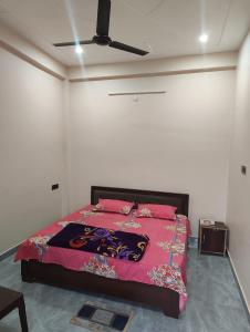 a bedroom with a bed with pink sheets and a ceiling at Prem Saroj homestay in Ayodhya