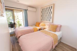 two beds in a room with a window at Jara - U19 Pandanus Palms Resort in Point Lookout +22 photos