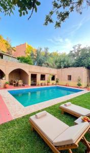 a swimming pool with two lounge chairs in the grass at Ouberge 'loassis house in Douar Azrou Melloul