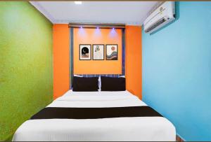 a small bedroom with an orange and green wall at KVS Residency in Tiruvallam